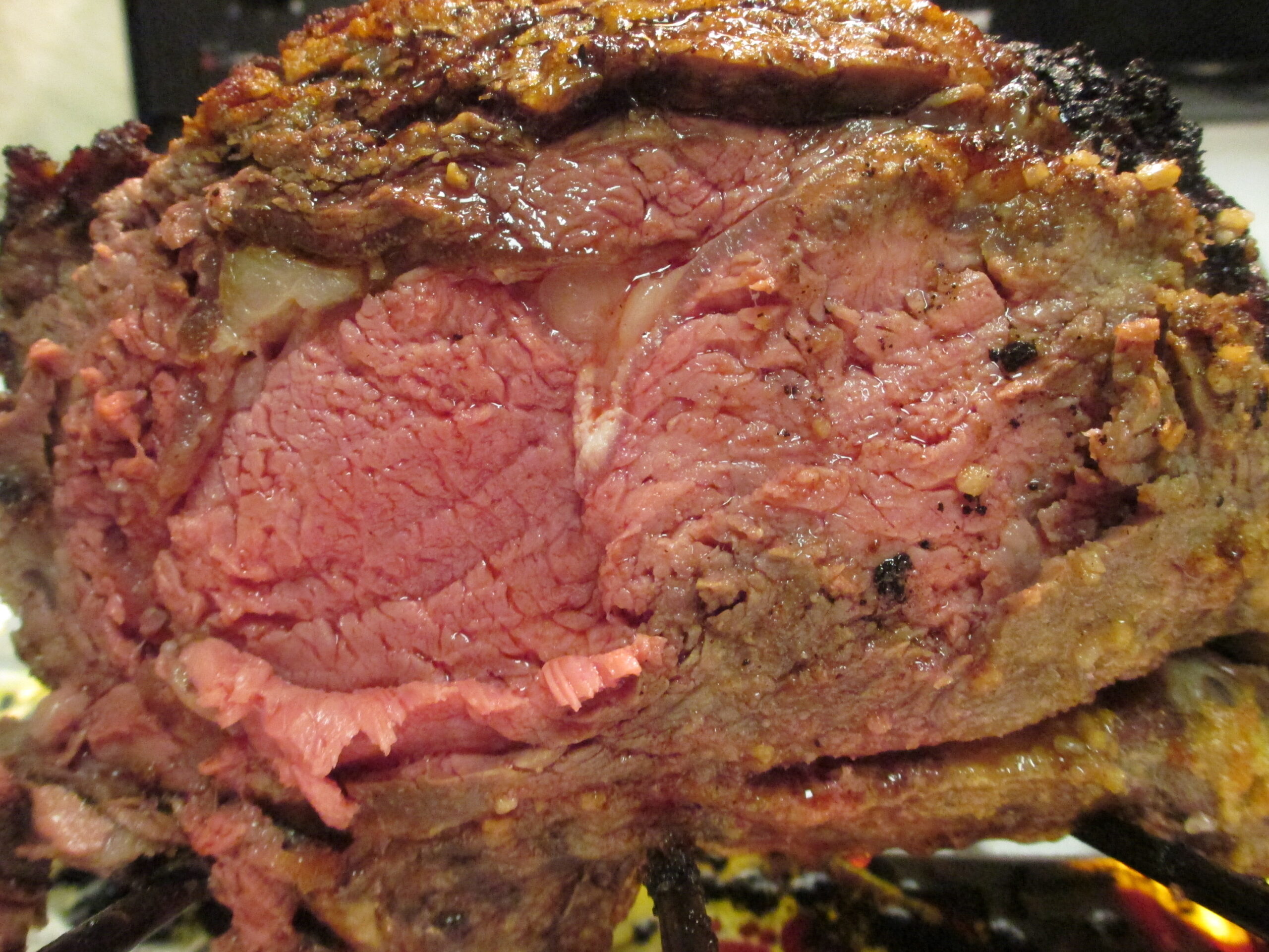 A perfectly cooked medium-rare prime rib roast resting in a roasting pan.