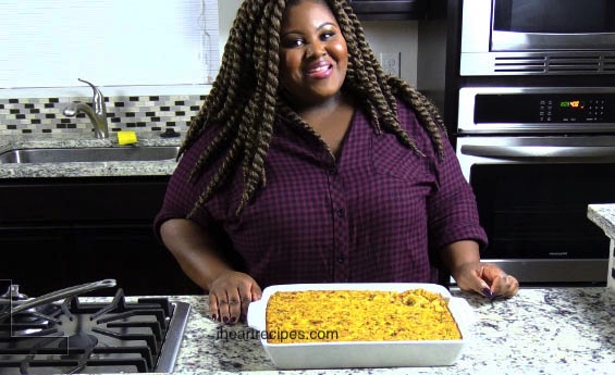 An image of Rosie standing in her kitchen, with a fresh baked dish of cornbread dressing on the countertop in front of her.