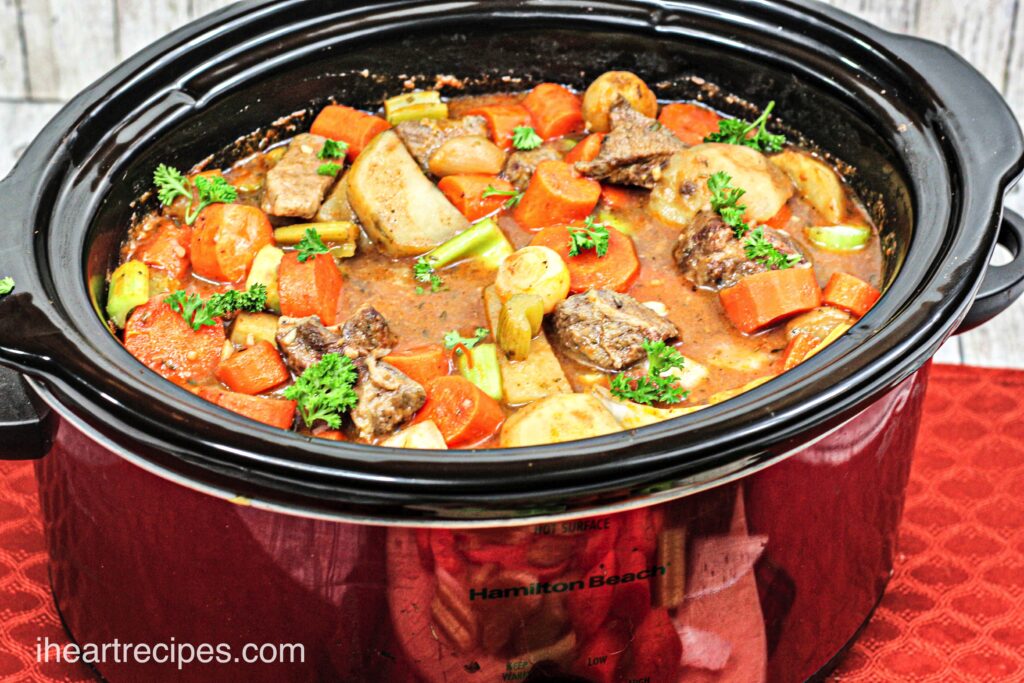 A large crockpot filled with beef stew -- chunky vegetables, potatoes, and tender beef in a hearty broth.