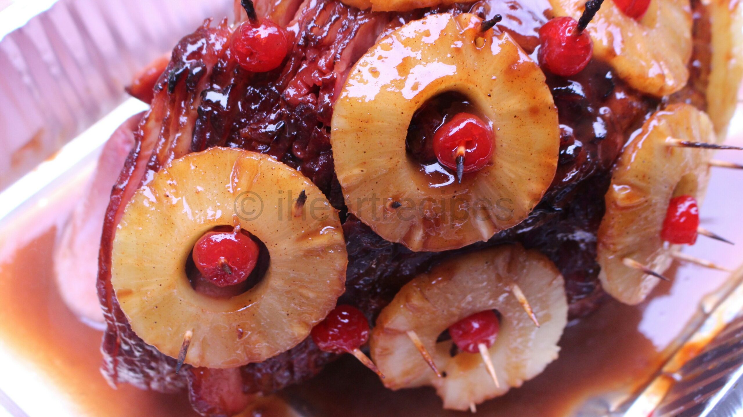 A spiral cut holiday ham covered in pineapple slices, cherries, and a sweet brown sugar glaze.