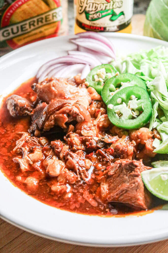 A closeup look at a hearty bowl of slow cooker pork pozole with jalapeno and lime garnish.