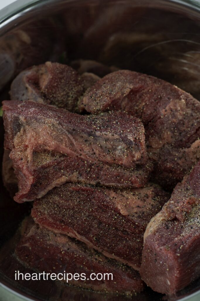 Chunks of seasoned beef resting in a crock pot. 