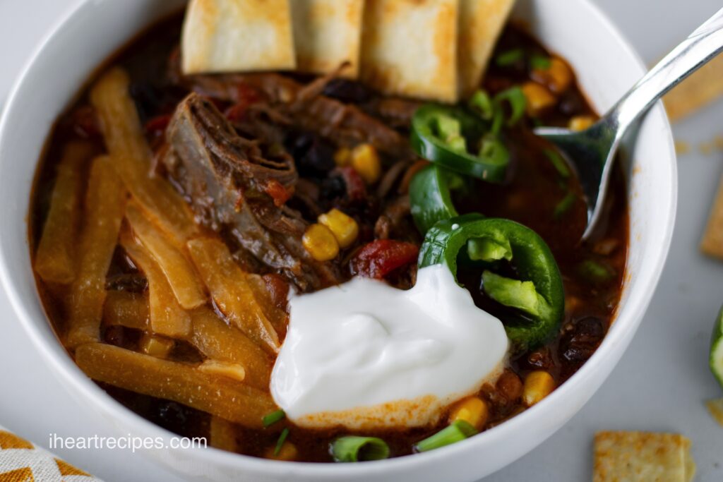 A white bowl filled with slow cooker beef brisket chili topped with a dollop of sour cream.