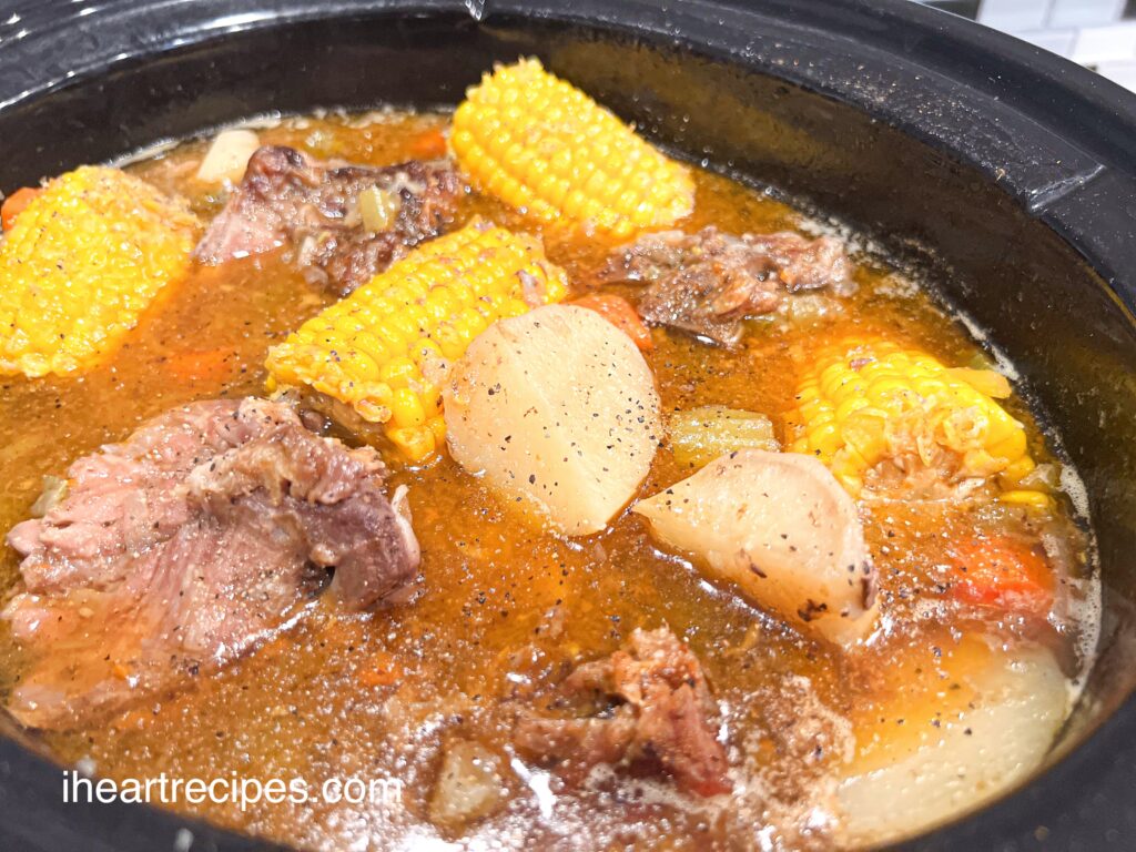 A black Crockpot filled with Pork Neck Bone Soup. 