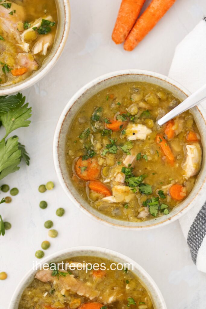 Chunks of smoked turkey, tender peas and bright carrots in a creamy broth served in a small cream-colored bowl. 
