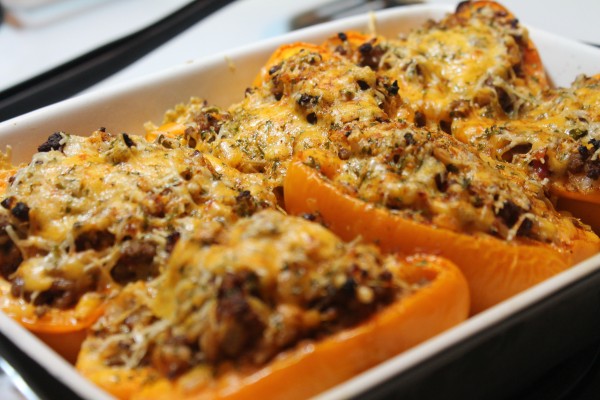 Baked orange stuffed peppers, filled with a cheesy ground beef and rice mixture, baked in a small casserole dish.