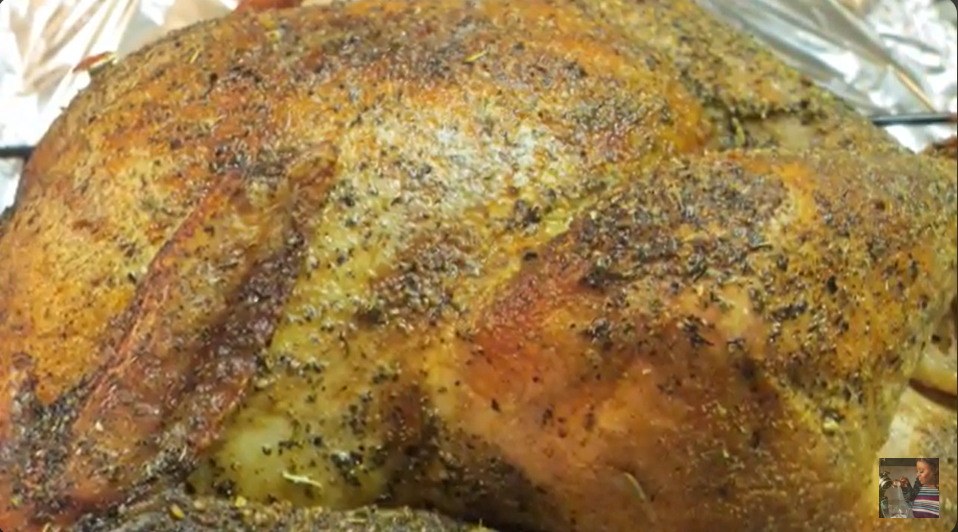 A closeup image of a perfectly roasted turkey, covered in savory seasonings and crispy, golden brown skin.