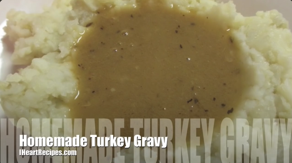 A screenshot from a recipe tutorial video shows mashed potatoes topped with a pool of gravy. Text across the bottom of the image says, "homemade turkey gravy" and "IHeartRecipes.com"